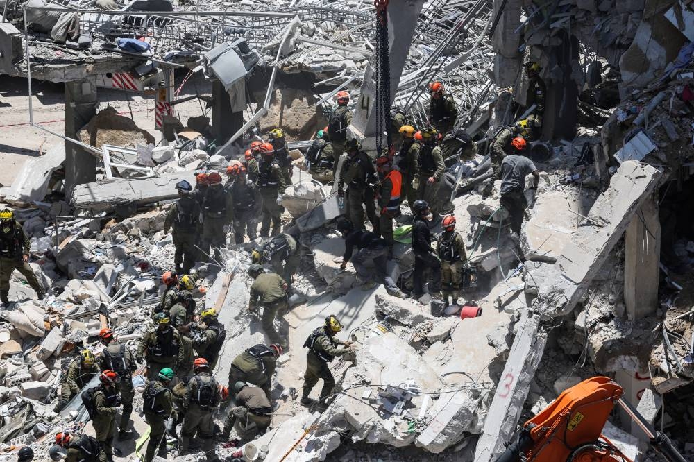 Rescue personnel work at an impact site following a missile attack from Iran, in Bat Yam, Israel, on Sunday. REUTERS