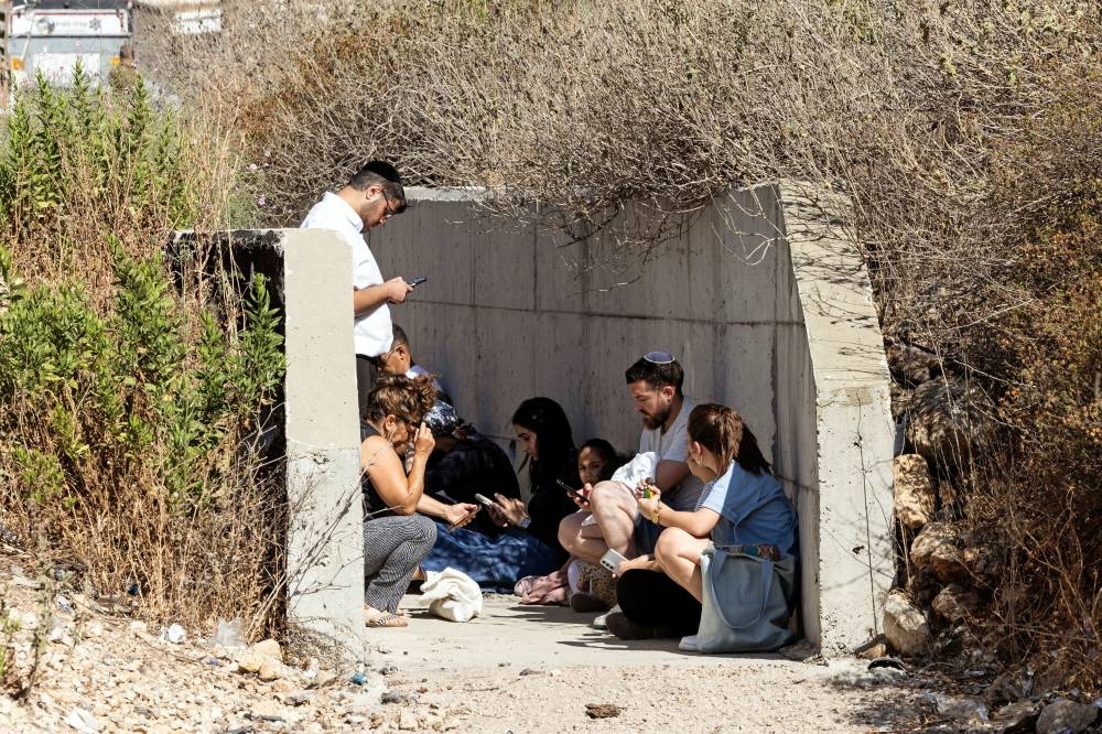 Israelis take shelter at the side of a highway as siren sounds following missile attack from Iran on Israel, in central Israel on Sunday. REUTERS
