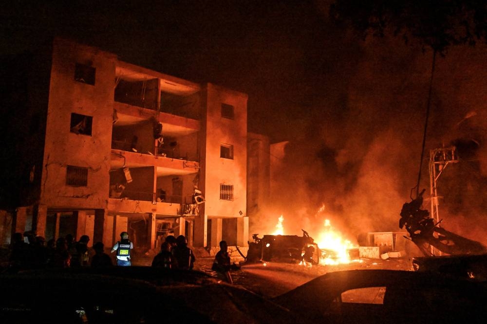 Firefighters and rescue personnel work at an impact site following missile attack from Iran on Israel, at Haifa, Israel, Sunday.
