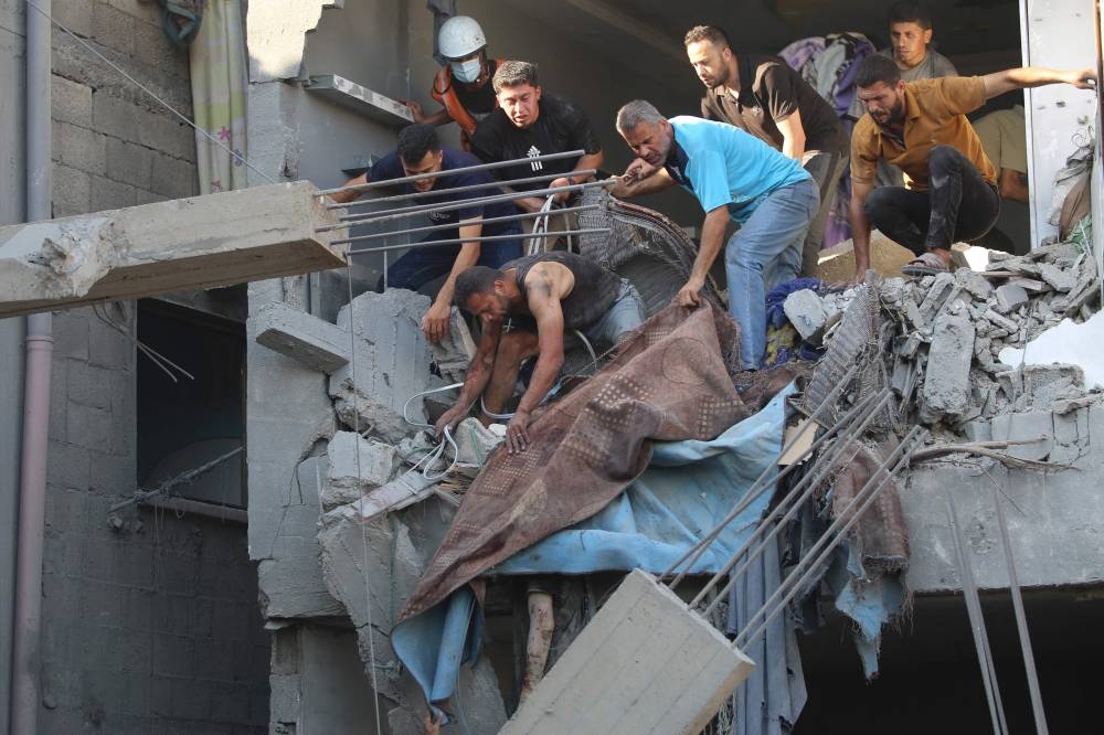 Palestinians try to reach a casualty in the rubble of a house targeted in an Israeli strike at the al-Nuseirat refugee camp in the central Gaza Strip Sunday.
