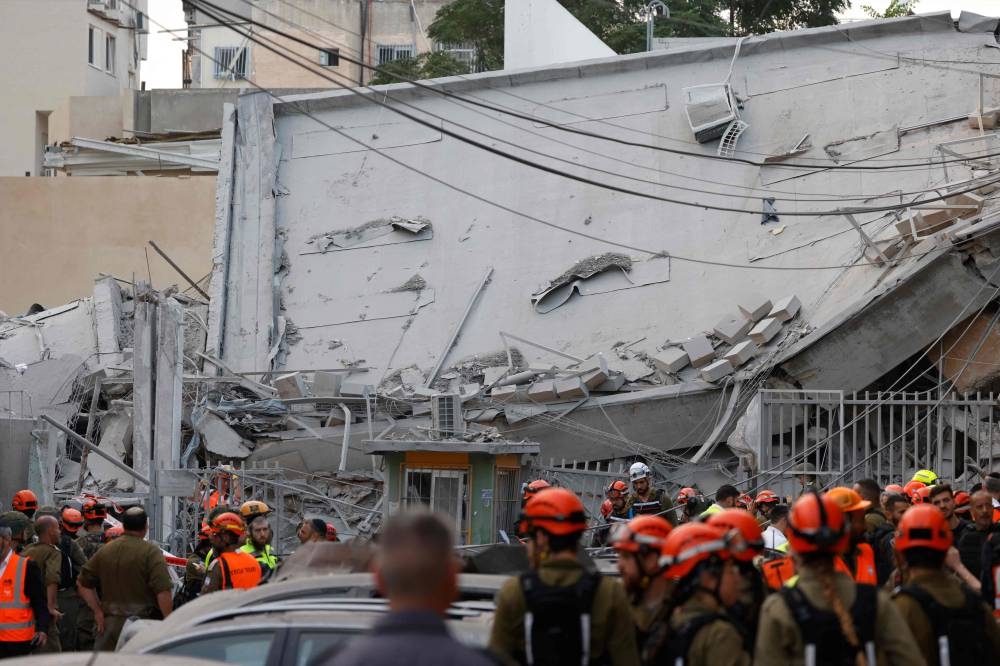 Rescuers work near a damaged building following a strike by an Iranian missile in the Israeli city of Bnei Brak, east of Tel Aviv, on Monday. AFP
