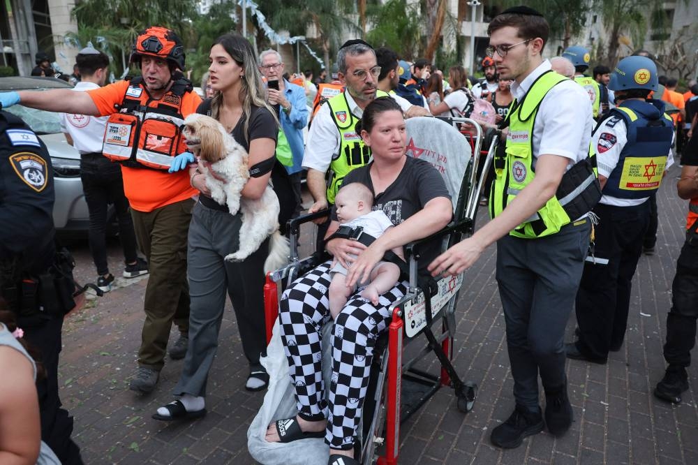 Responders attend to a woman and a baby near a damaged building following a strike by an Iranian missile in the Israeli city of Petah Tikva, east of Tel Aviv, on Monday. AFP