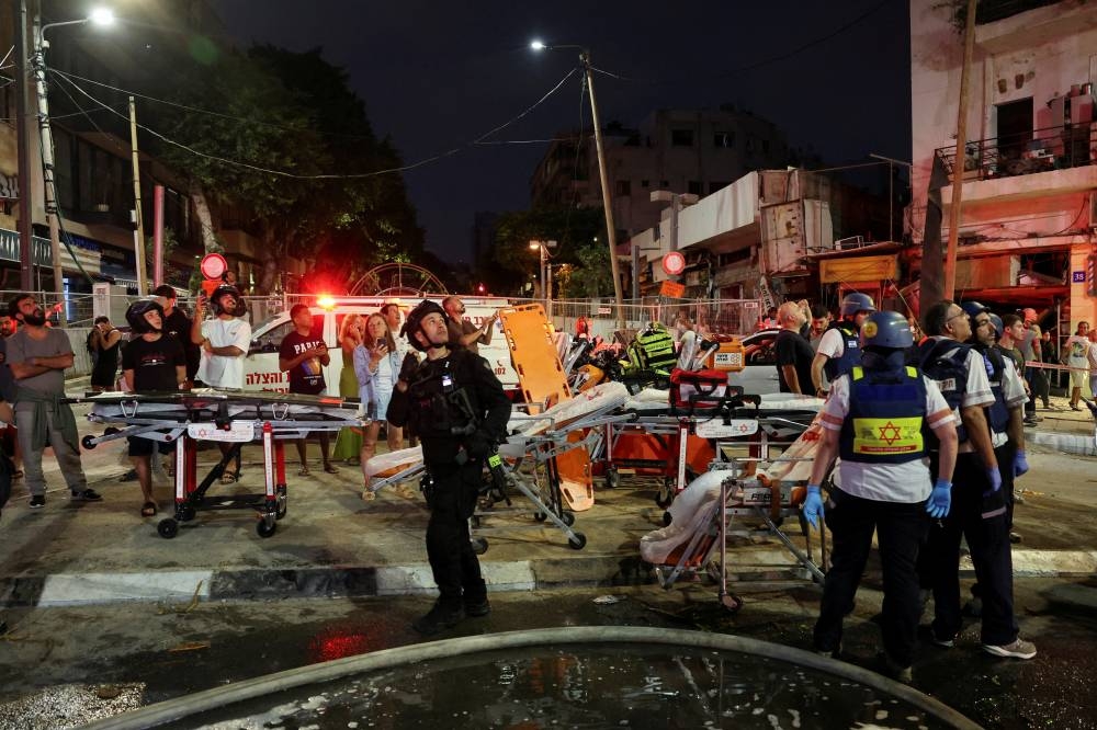 Emergency personnel operate after missiles were launched from Iran to Israel, in Tel Aviv, Israel, on Monday. REUTERS