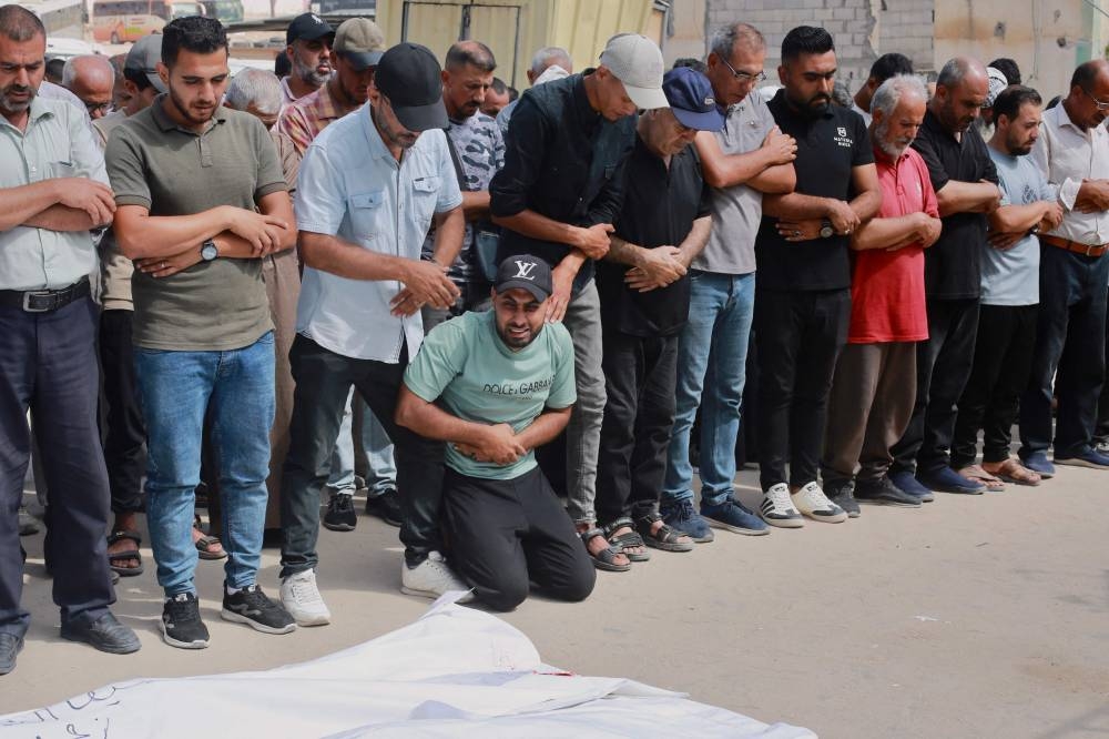 Palestinians pray during the funeral of relatives, killed in Israeli strikes, in Khan Yunis in the southern Gaza Strip on Monday. AFP