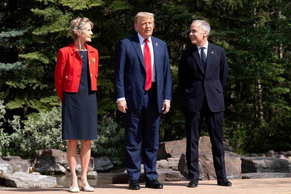 Trump poses for a photo with Diana Fox Carney and Prime Minister of Canada Mark Carney, as he arrives at the G7 leaders' summit in Kananaskis, Alberta, Canada Monday.