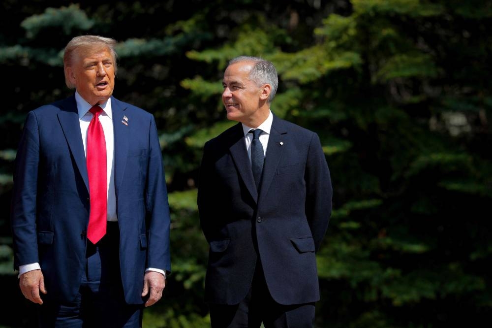 Canadian Prime Minister Mark Carney (R) greets Trump at the official welcome ceremony during the G7 Leaders' Summit Monday in Kananaskis, Alberta.