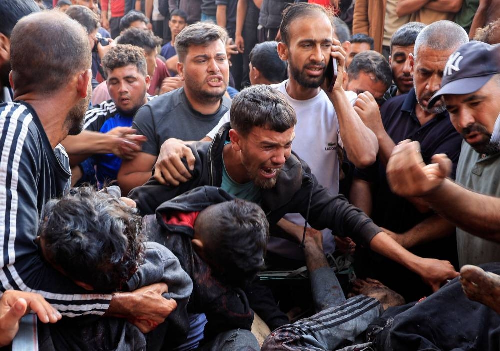 Palestinians react next to people wounded in an Israeli strike while waiting for aid, at Nasser hospital, in Khan Younis, southern Gaza Strip, on Tuesday. REUTERS