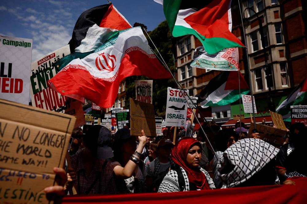 Protesters wave Palestinian and Iranian flags and hold placards reading "Stop arming Israel" as they gather in Russell Square to take part in a march through central London, on Saturday. AFP