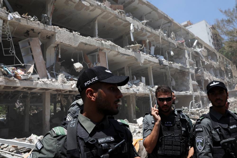 Israeli border police officers work at an impact site following a missile attack from Iran on Israel, amid the Iran-Israel conflict, in Tel Aviv, on Sunday. REUTERS
