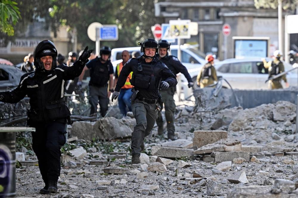 Security forces run as a second siren sounds at an impacted site, as they work following an earlier missile attack from Iran, in Haifa, on Sunday. REUTERS