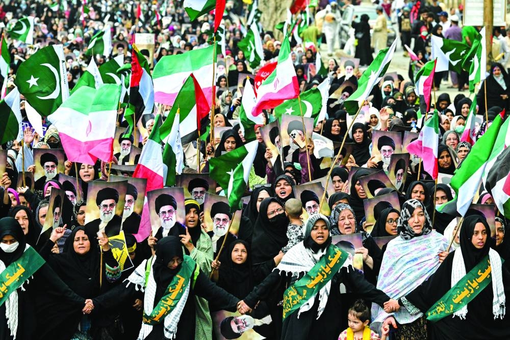 Protesters holding portraits of Iran’s Supreme leader Ayatollah Ali Khamenei to condemn US and Israel’s attacks on Iran in Karachi Sunday. AFP