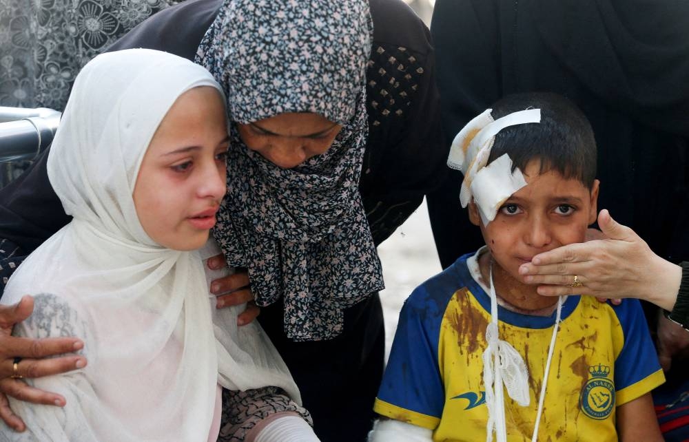 An injured boy and other mourners react during the funeral of Palestinians who were killed by Israeli fire while trying to receive aid in central Gaza Strip, according to the Gaza Health Ministry, at Al-Shifa hospital, in Gaza City, on Tuesday. REUTERS