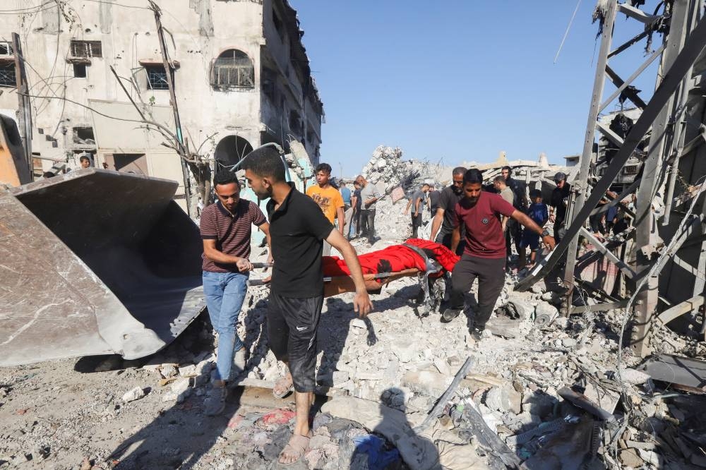 Palestinians carry a casualty at the site of an overnight Israeli strike on a fuel station where displaced people shelter, in Gaza City, on Wednesday. REUTERS