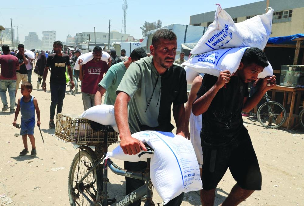 
Palestinians carry sacks of flour in Khan Younis, in the southern Gaza Strip, yesterday. 