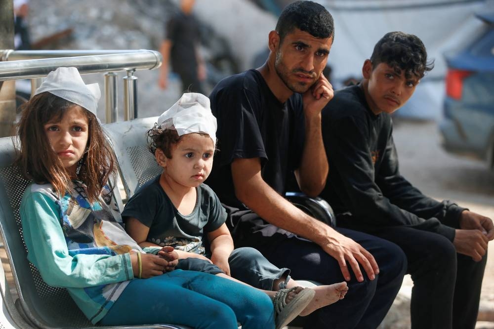 Injured Palestinian girls attend the funeral of their father, who was killed in an Israeli air strike, at Al-Shifa Hospital in Gaza City, on Friday. REUTERS