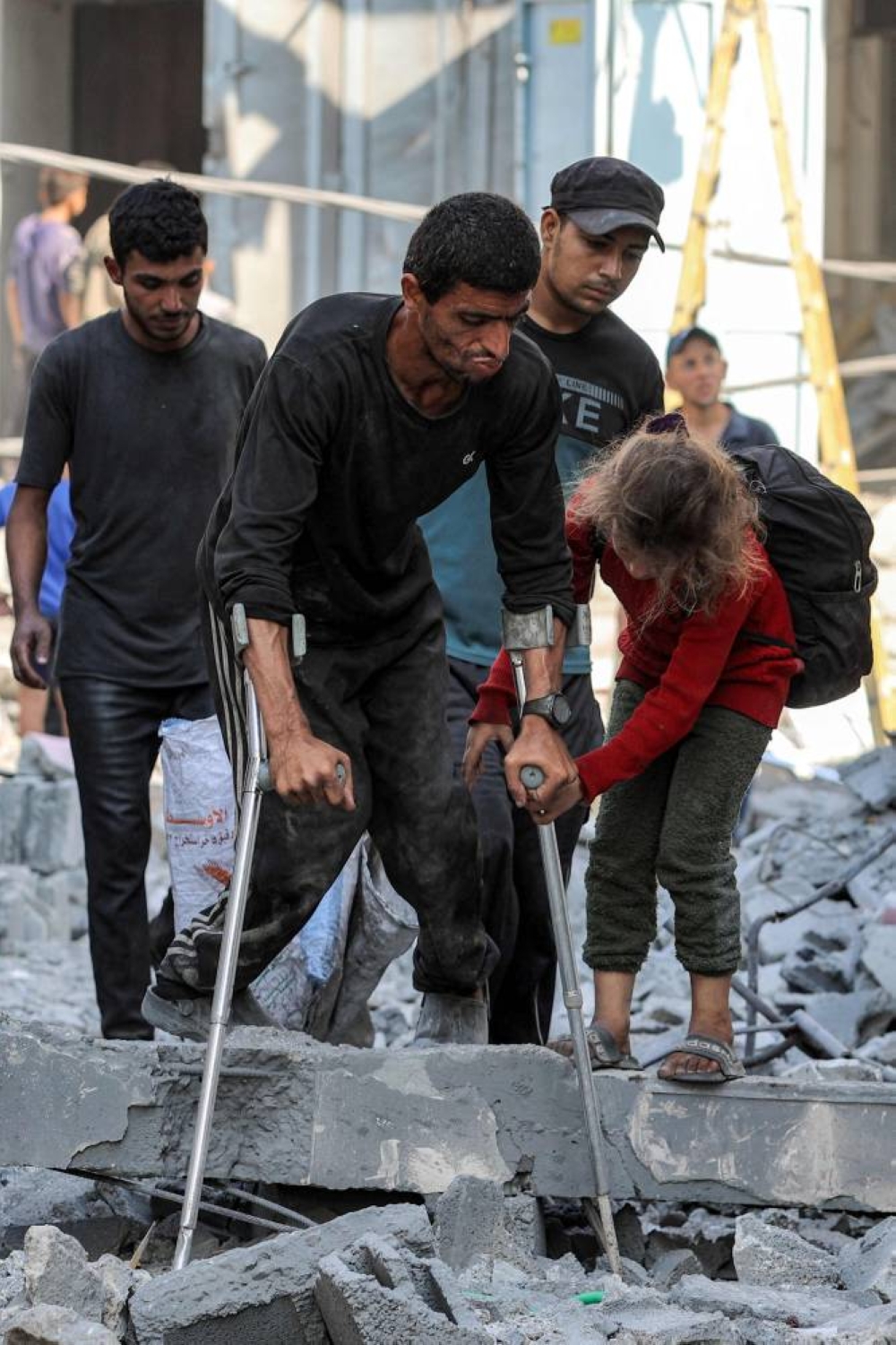 A girl helps a man with crutches walk through rubble following Israeli strikes in Jabalia in the northern Gaza Strip, on Friday. AFP