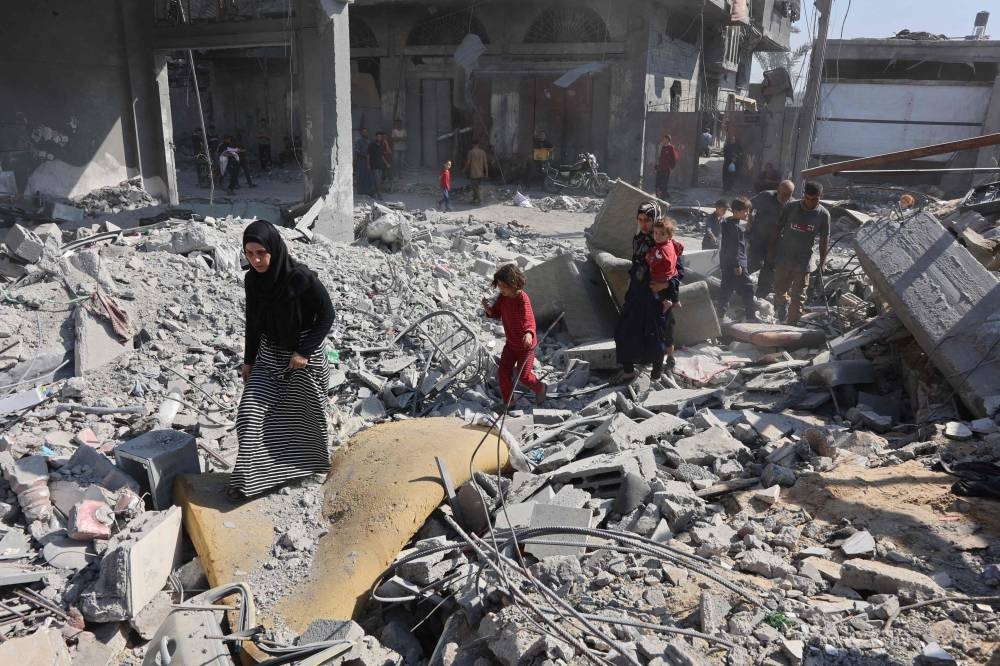 Palestinians walk through through rubble following Israeli strikes in Jabalia in the northern Gaza Stri, on Friday. AFP