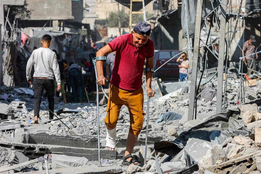 A man walks with crutches through rubble following Israeli strikes in Jabalia in the northern Gaza Strip, on Friday. AFP