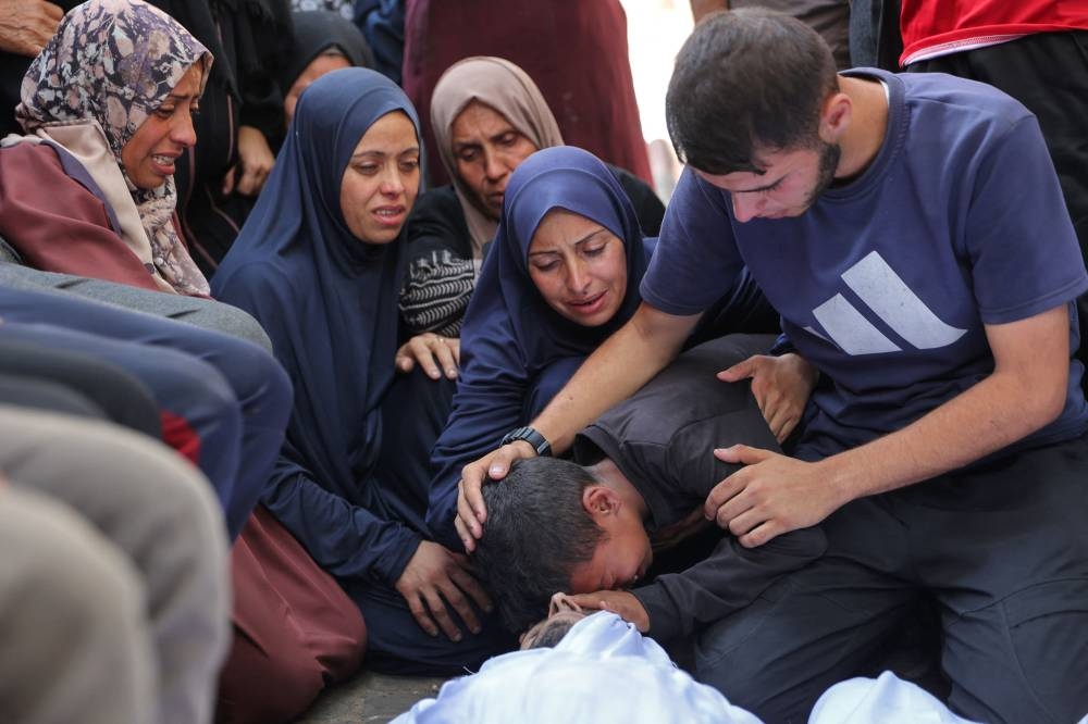 Palestinians mourn over the bodies of loved ones killed during overnight Israeli strikes, on the grounds of Al-Shifa hospital in the central Gaza Strip on Saturday. AFP