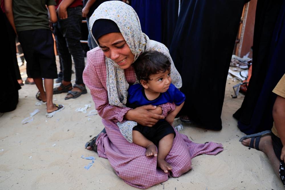 A mourner reacts while holding a child during the funeral of Palestinians killed in an overnight Israeli strike on a tent, according to Gaza's health ministry, at Nasser Hospital in Khan Younis, southern Gaza Strip, on Sunday. REUTERS