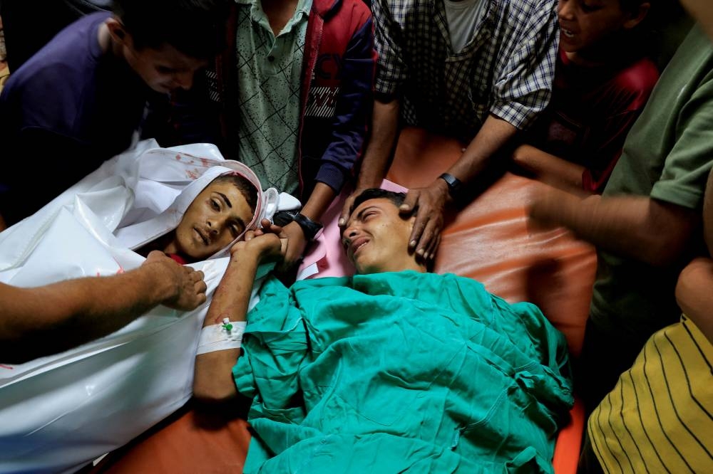 A Palestinian injured in an overnight Israeli strike on a tent, bids farewell to his brother, who was killed in the same strike, according to Gaza's health ministry, at Nasser Hospital in Khan Younis, southern Gaza Strip, on Sunday. REUTERS