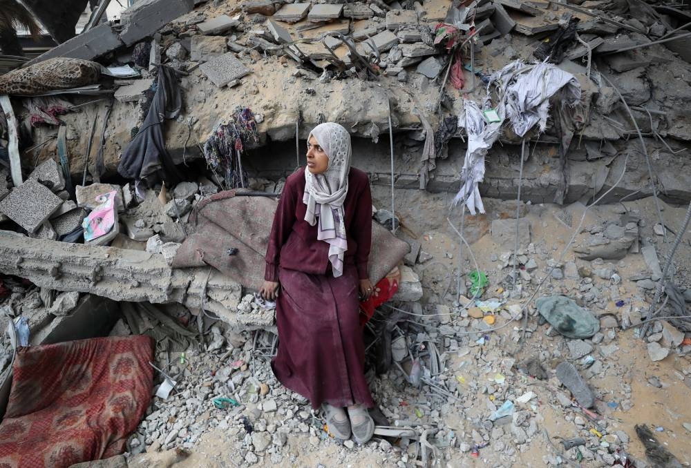 A Palestinian woman sits amidst the damage at an UNRWA school sheltering displaced people that was hit in an Israeli air strike on Sunday, in Gaza City, on Monday. REUTERS