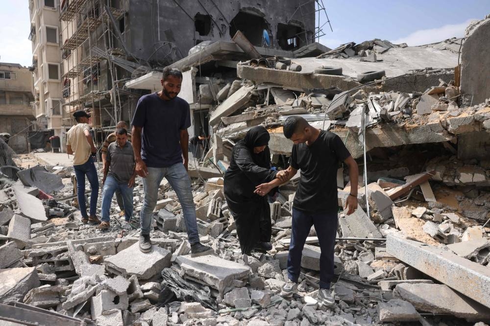 Palestinians walk on the rubble of a residential house that was hit in overnight Israeli strikes in Jabalia in the northern Gaza Strip, on Monday. AFP
