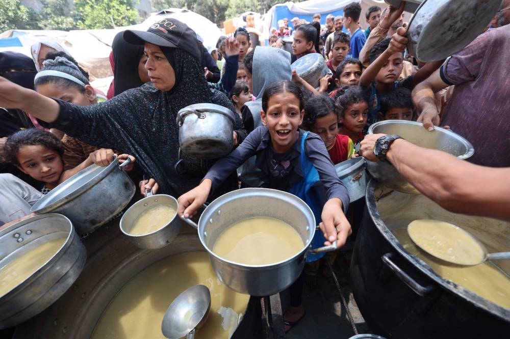 Palestinian children line up to receive a hot meal at a food distribution point in Nuseirat on, Monday. AFP