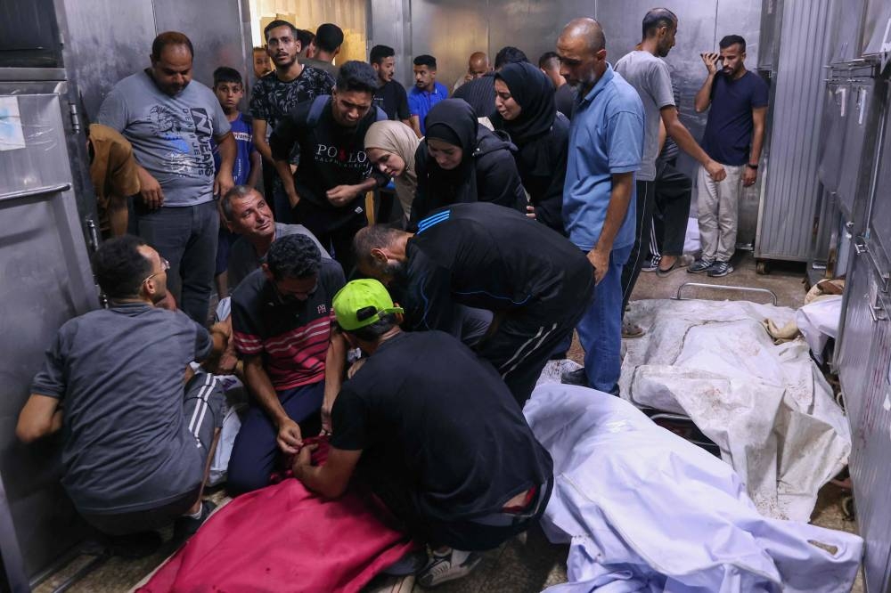 Palestinians mourn by bodies of relatives killed in an Israeli strike on Al-Baqa cafeteria on Gaza City seafront, at the city's Al-Shifa hospital on Monday. AFP