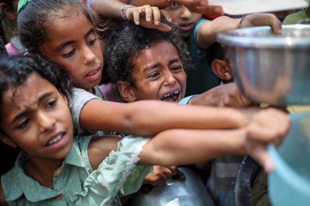 Palestinian children line up to receive a hot meal at a food distribution point in Nuseirat on Monday. AFP