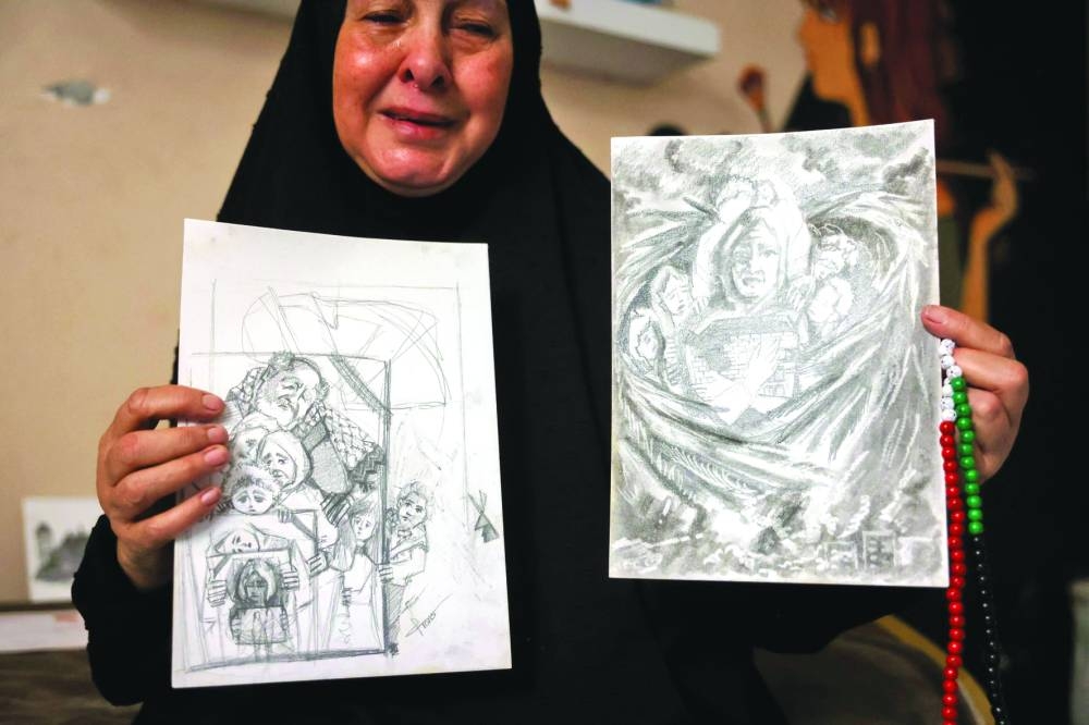 The mother of Palestinian visual artist Franz al-Salmi, who was killed in an Israeli strike on a coffee shop in Gaza City on June 30, holds drawings made by the artist as she sits in her studio, Tuesday.