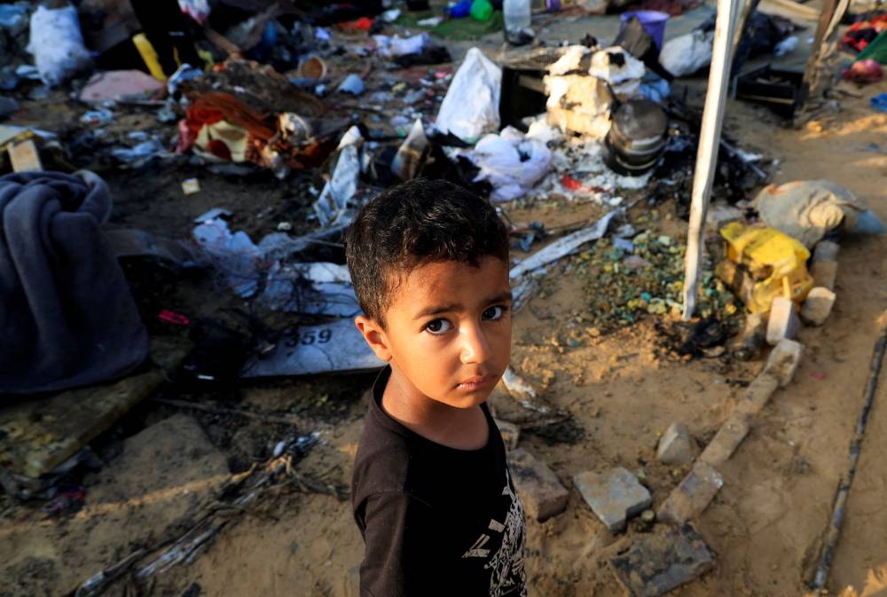 A Palestinian boy stands near the damage at the site of an overnight Israeli air strike on a tent sheltering displaced people, in Khan Younis, southern Gaza Strip, on Wednesday. REUTERS