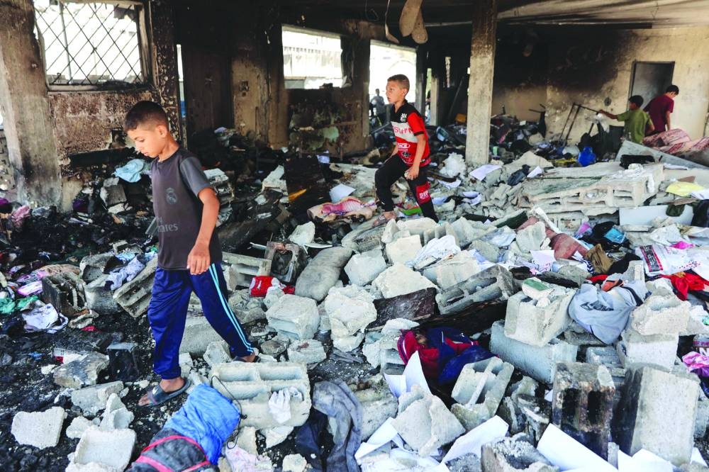 Children walk over debris at Mustafa Hafez school, sheltering Palestinians, following an overnight Israeli strike in Gaza City, Thursday 
