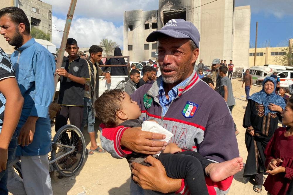 A man carries a child as he joins mourners attending the funeral of Palestinians killed in Israeli strikes on the southern Gaza Strip the previous day, outside the Nasser Hospital in Khan Yunis, on Friday. AFP