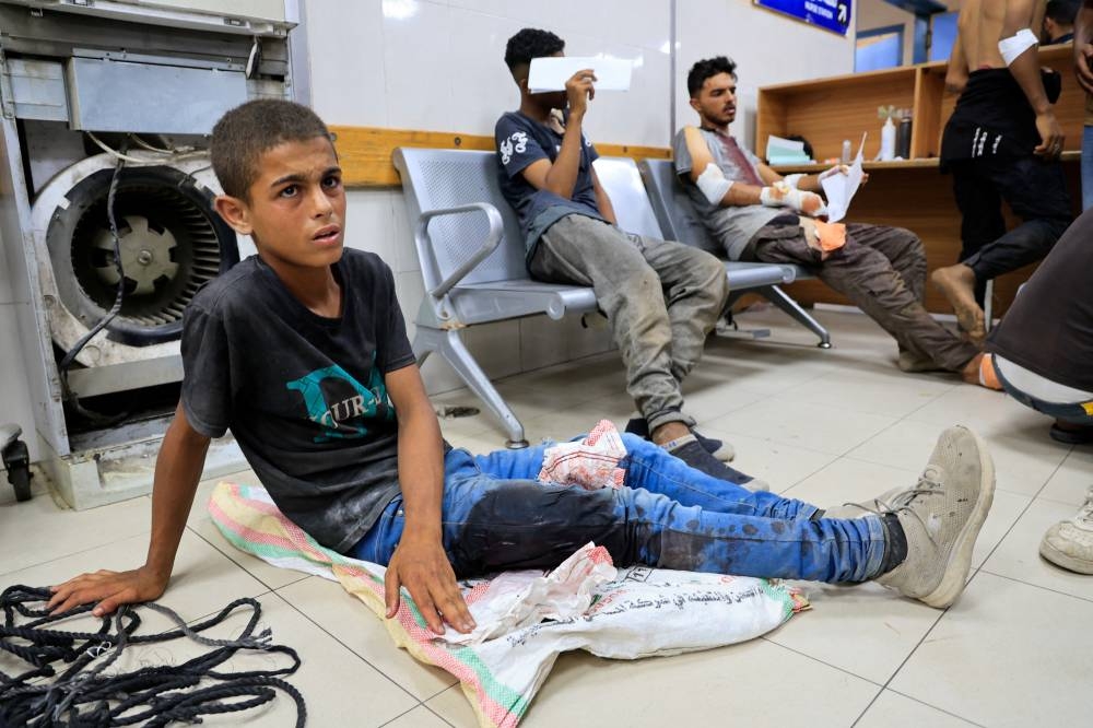 A Palestinian, wounded by Israeli fire while seeking aid on Friday, according to medics, sits on the floor at Nasser Hospital in Khan Younis, southern Gaza Strip, on Friday. REUTERS