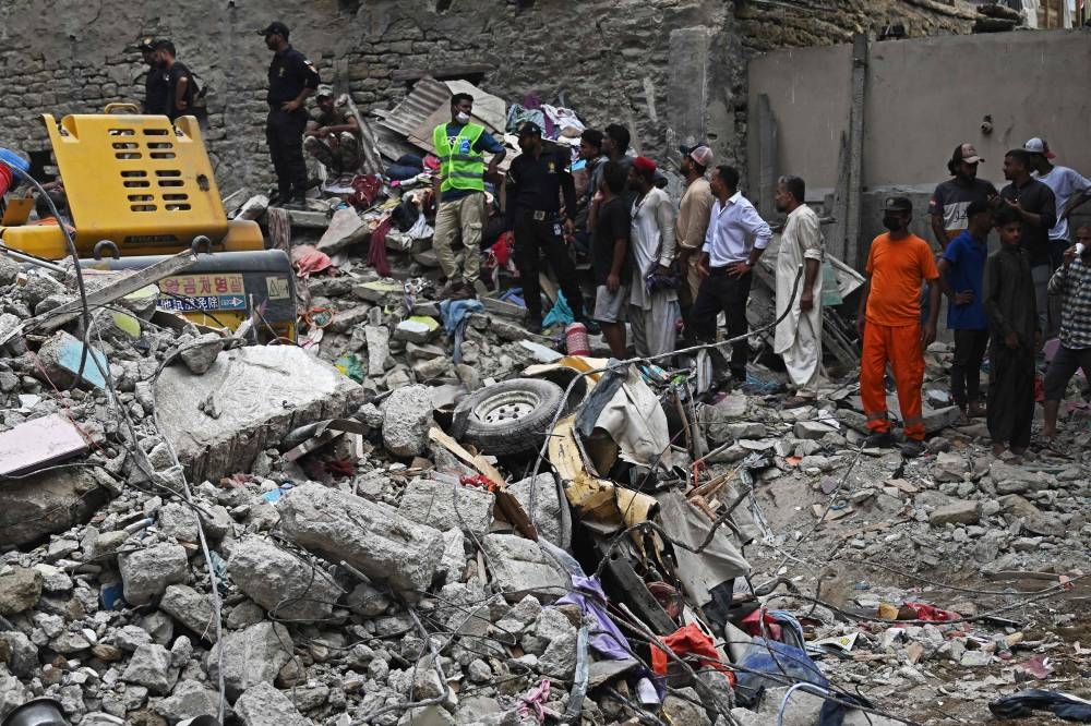 Rescue workers conduct a search operation amid the debris of a collapsed residential building in Karachi on Saturday. AFP