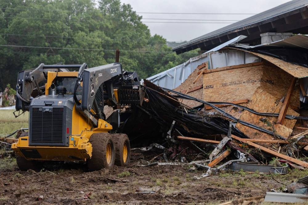 Search and rescue workers dig through debris looking for any survivors or remains of people swept up in the flash flooding on Sunday in Hunt, Texas. AFP