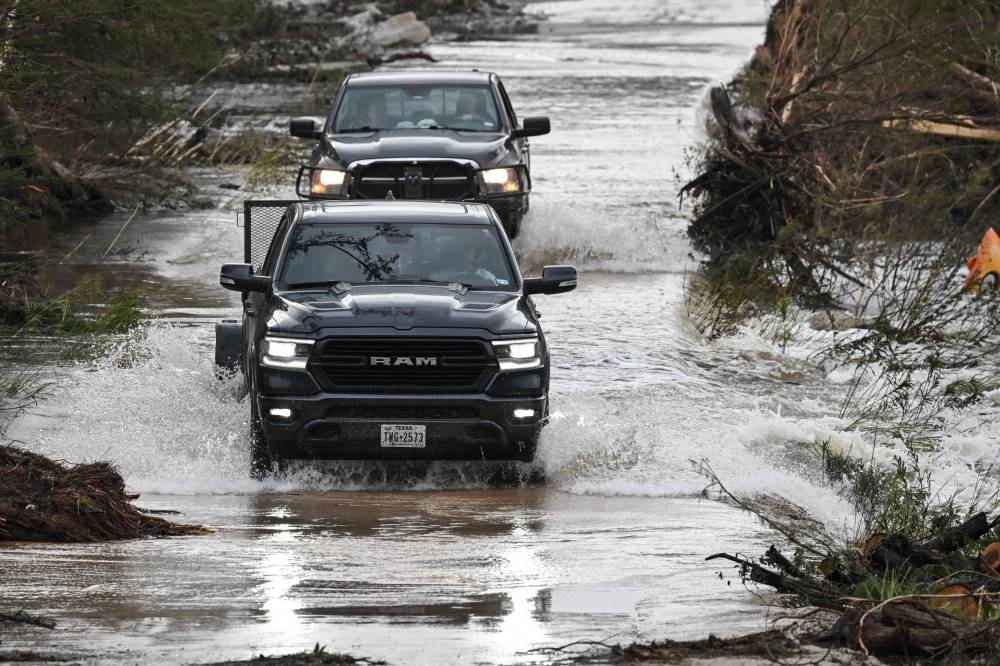 Trucks drive through a flooded and damaged road in Hunt, Texas, on Sunday, following severe flash flooding that occurred during the July 4 holiday weekend. AFP