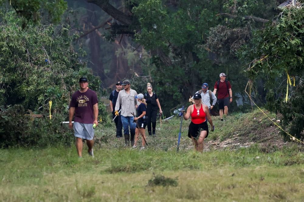 People search the area, following flash flooding, in Hunt, Texas, on Sunday. REUTERS