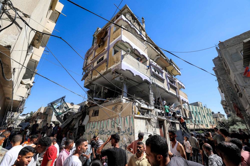 People gather outside a building that was hit by Israeli bombardment in the Nuseirat camp in the central Gaza Strip Sunday.