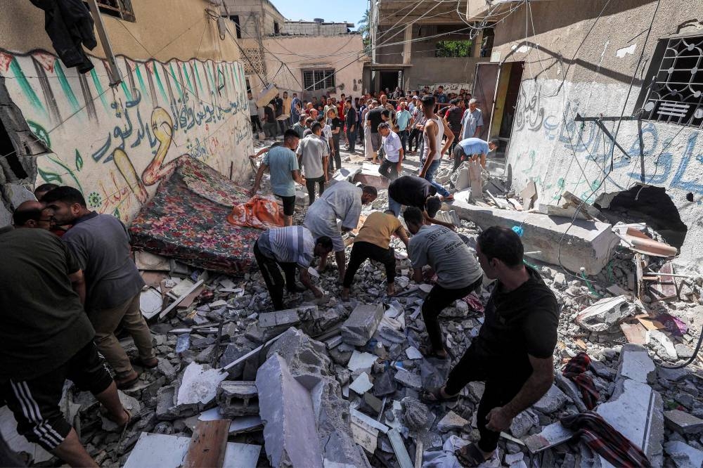 People search the rubble of a building that was hit by Israeli bombardment in the Nuseirat camp in the central Gaza Strip Sunday.