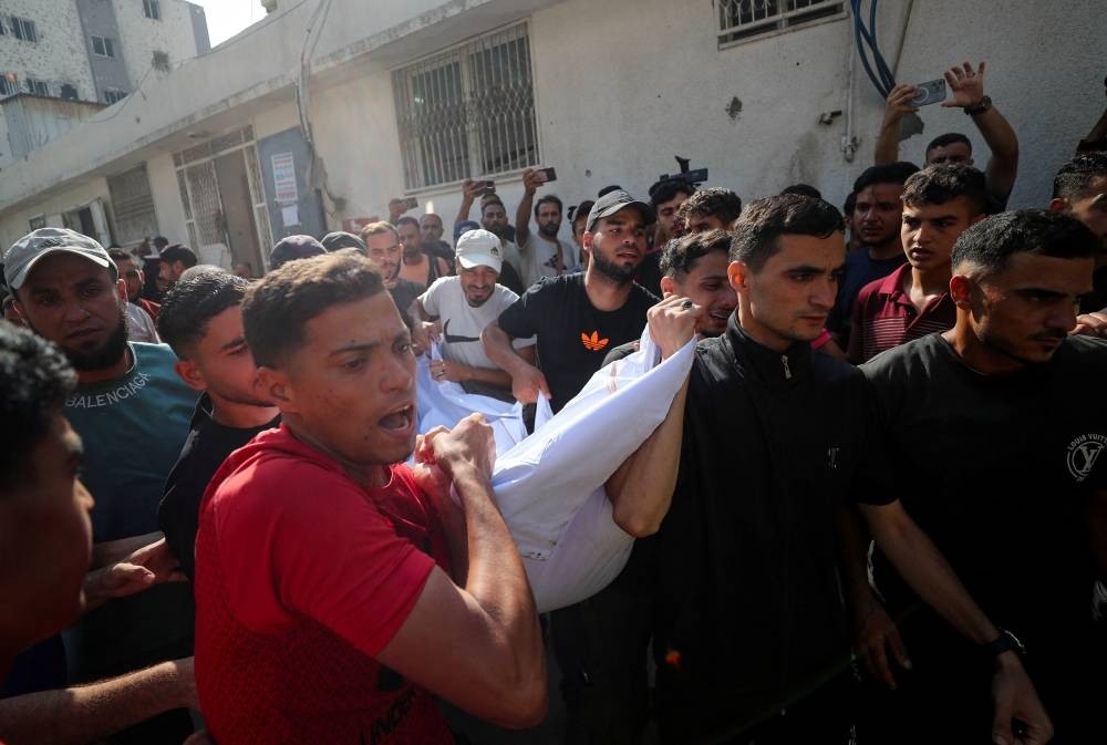 Mourners carry a body as they attend the funeral of Palestinians killed in overnight Israeli strikes, according to medics, at Al-Shifa Hospital in Gaza City, Friday. REUTERS