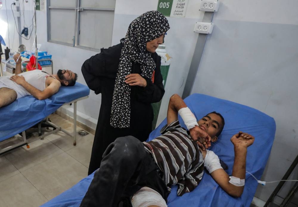 A Palestinian boy, wounded in an Israeli strike that killed people, who gathered to collect water from a distribution point, receives treatment at Al-Awda Hospital in Nuseirat in the central Gaza Strip, on Sunday. REUTERS