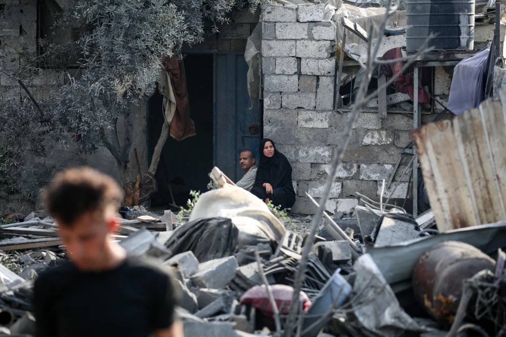 Palestinians sit amid the rubble of a house in the aftermath of an overnight Israeli strike that hit Nuseirat in the central Gaza Strip, on Sunday. AFP