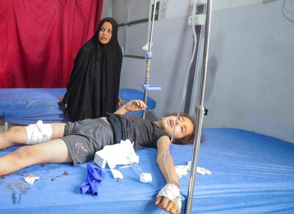 A Palestinian girl, wounded in an Israeli strike that killed people, who gathered to collect water from a distribution point, according to medics, receives treatment at Al-Awda Hospital in Nuseirat in the central Gaza Strip, on Sunday. REUTERS