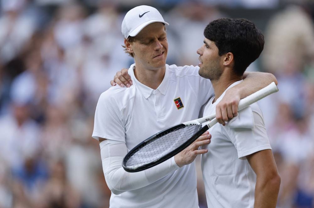 Tennis - Wimbledon - All England Lawn Tennis and Croquet Club, London, Britain - July 13, 2025 Italy's Jannik Sinner reacts with Spain's Carlos Alcaraz after winning the men's final REUTERS/Stephanie Lecocq