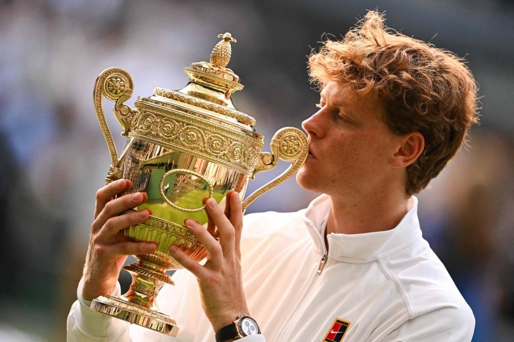 Italy's Jannik Sinner kisses his winner's trophy as he poses for pictures following his victory against Spain's Carlos Alcaraz at the end of their men's singles final tennis match on the fourteenth day of the 2025 Wimbledon Championships at The All England Lawn Tennis and Croquet Club in Wimbledon, southwest London, on July 13, 2025. (Photo by Kirill KUDRYAVTSEV / AFP) / RESTRICTED TO EDITORIAL USE