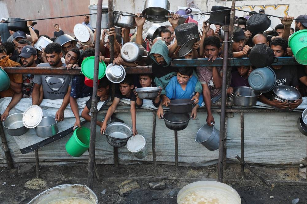 Palestinians wait to receive food from a charity kitchen, amid a hunger crisis, in Gaza City, Monday.