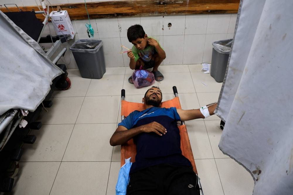 A Palestinian man lies on a stretcher as he receives treatment after being wounded in morning Israeli strikes on tents sheltering displaced people, according to medics, at Nasser Hospital in Khan Younis, southern Gaza Strip, on Monday. REUTERS