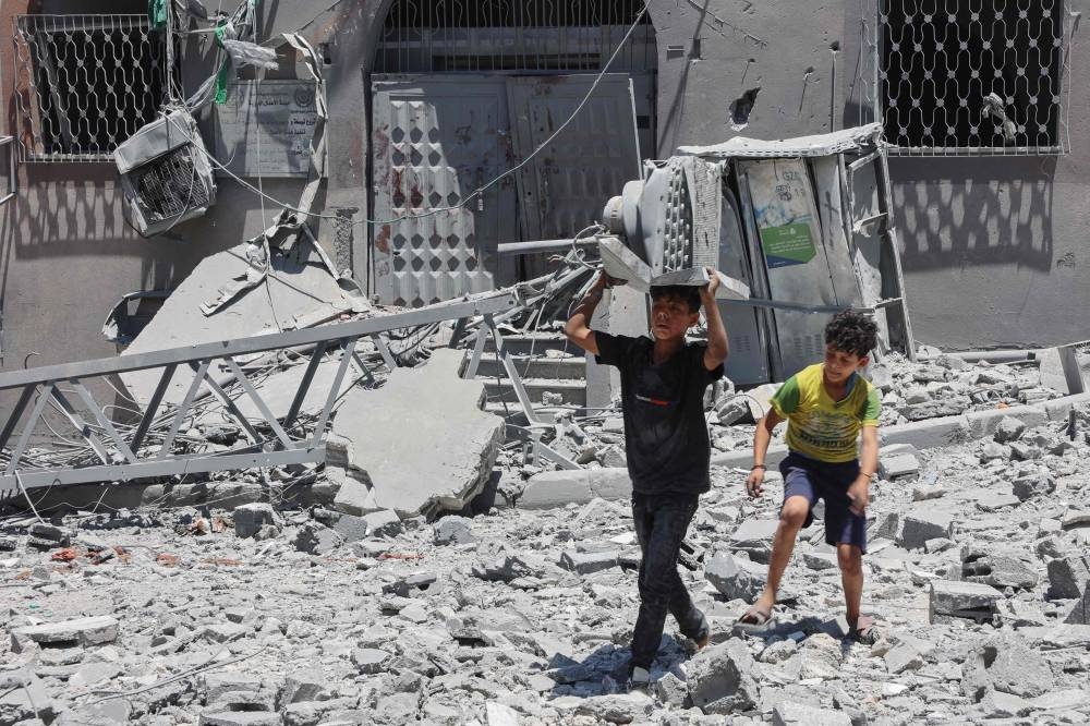 Palestinian boys search for items to salvage in the rubble of buildings destroyed a day earlier in Israeli strikes on Al-Daraj neighbourhood in Gaza City, Wednesday.